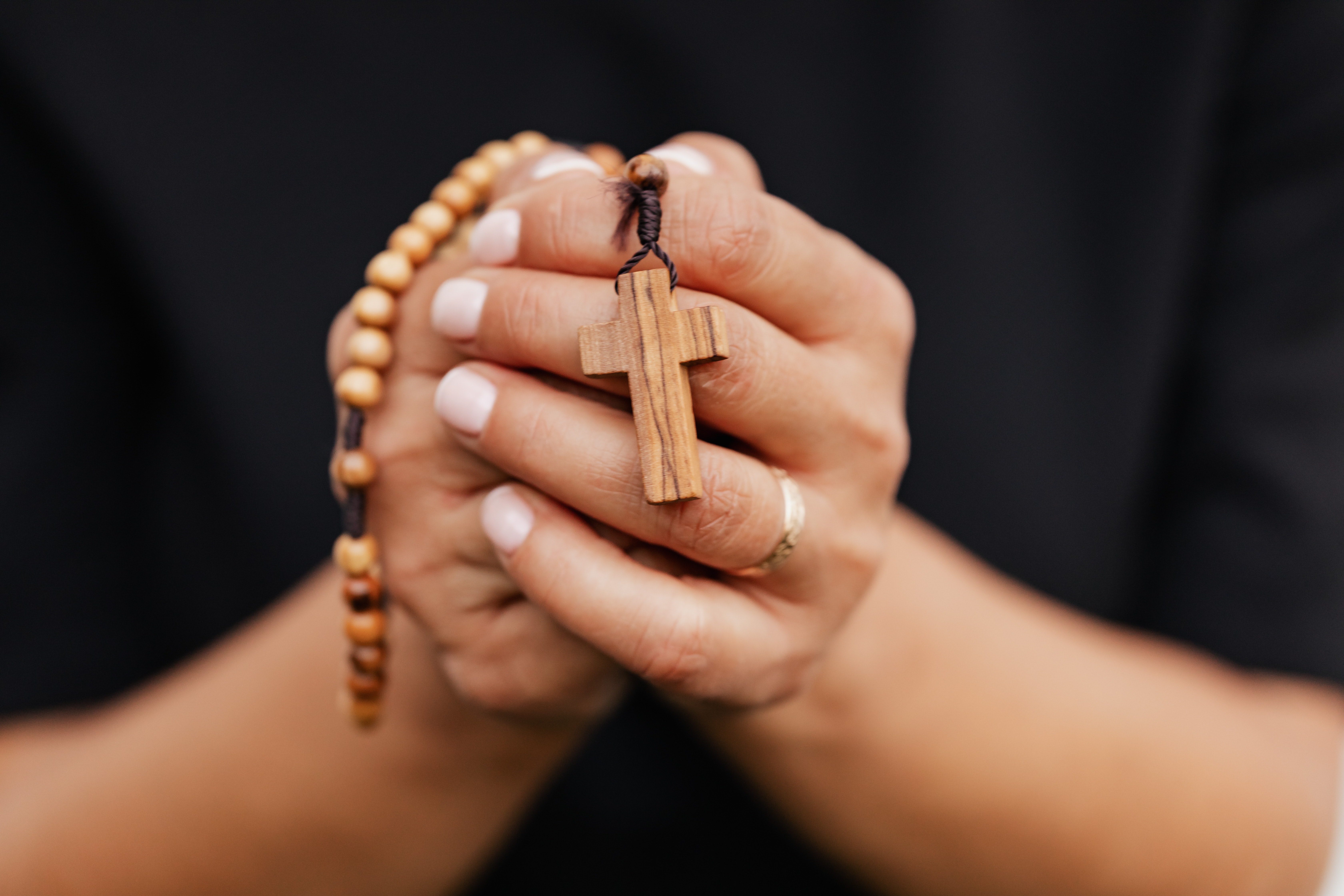 hands holding a wooden rosary